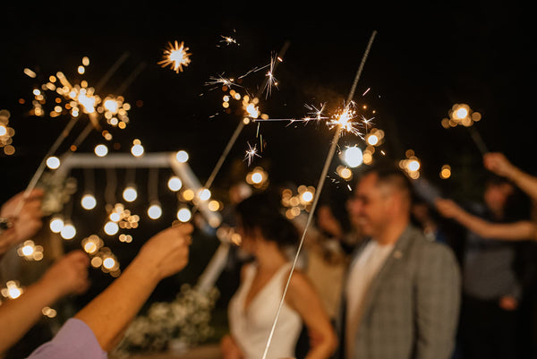 couple surrounded by crowd holding sparklers