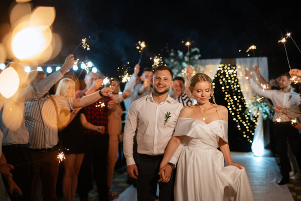 newly wed couple walking in the middle of a crowd that holds sparklers