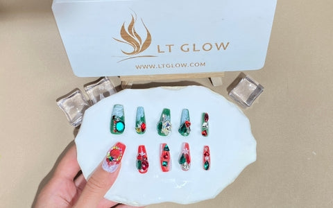 A collection of vibrant handcraft fake nails with intricate holiday-themed designs, including greenery and festive patterns, presented on a white palette against the backdrop of the LT GLOW logo