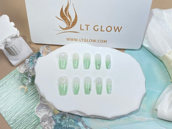 Élégant ensemble de faux ongles faits main de LTGlow présenté sur une palette ovale blanche, accompagné d'un emballage de marque et d'accentuations décoratives