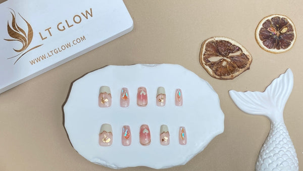 Decorative set of false nails displayed on a white scalloped tray, accompanied by the LT Glow logo and dried citrus slices