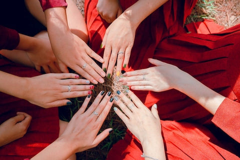 Six women's hands coming together, each showcasing a unique hand-painted design on LT Glow handmade press-on nails, celebrating the art of nail customization