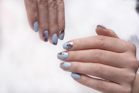Close-up of woman's fingers adorned with blue hand-drawn glitter design on LT Glow handcrafted fake nails