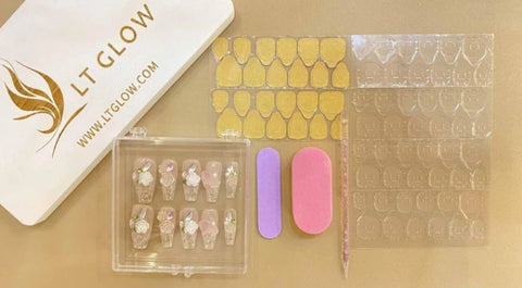 A neatly arranged set of handcraft press-on nails with intricate designs, displayed alongside adhesive tabs, a nail file, and a buffer, with the LTGLOW logo in the background