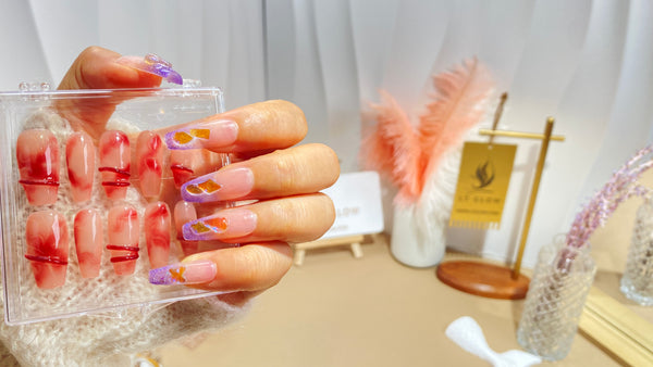 Hand showcasing a set of acrylic nail designs with a backdrop of beauty accessories