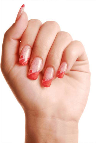 A clenched fist displaying press-on nails with a sparkling red gradient, exemplifying a simple yet elegant manicured look