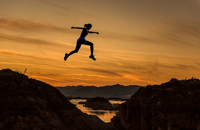 Woman jumping between rocks at sunset