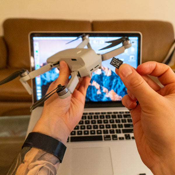 Picture of drone being held in front of a MacBook laptop