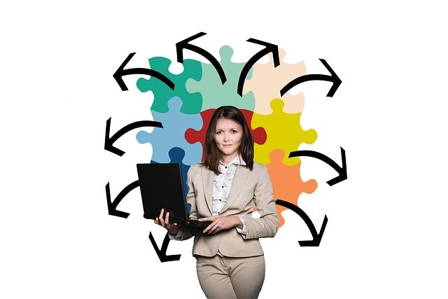 Businesswoman holding computer with puzzle pieces behind her