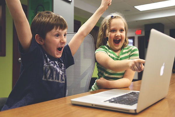 Two children excited about what is on laptop