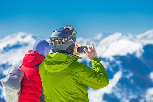 Two people filming top of ski hill