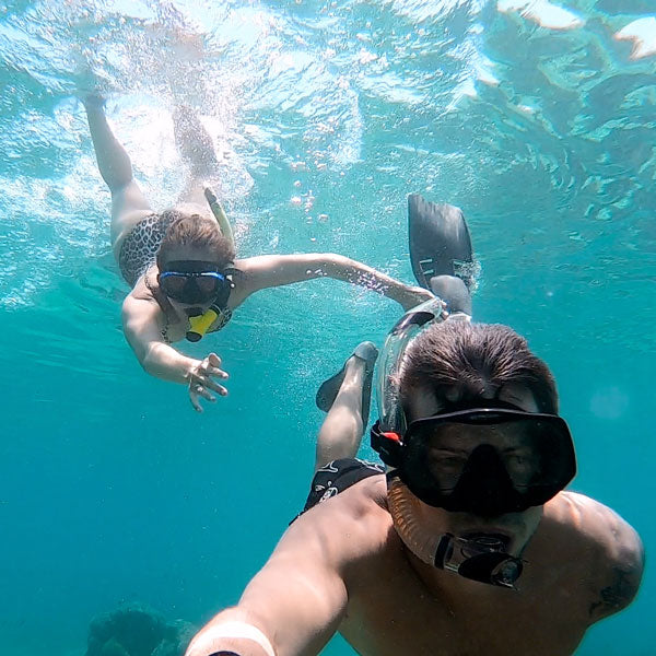 Two people filming themselves swimming underwater