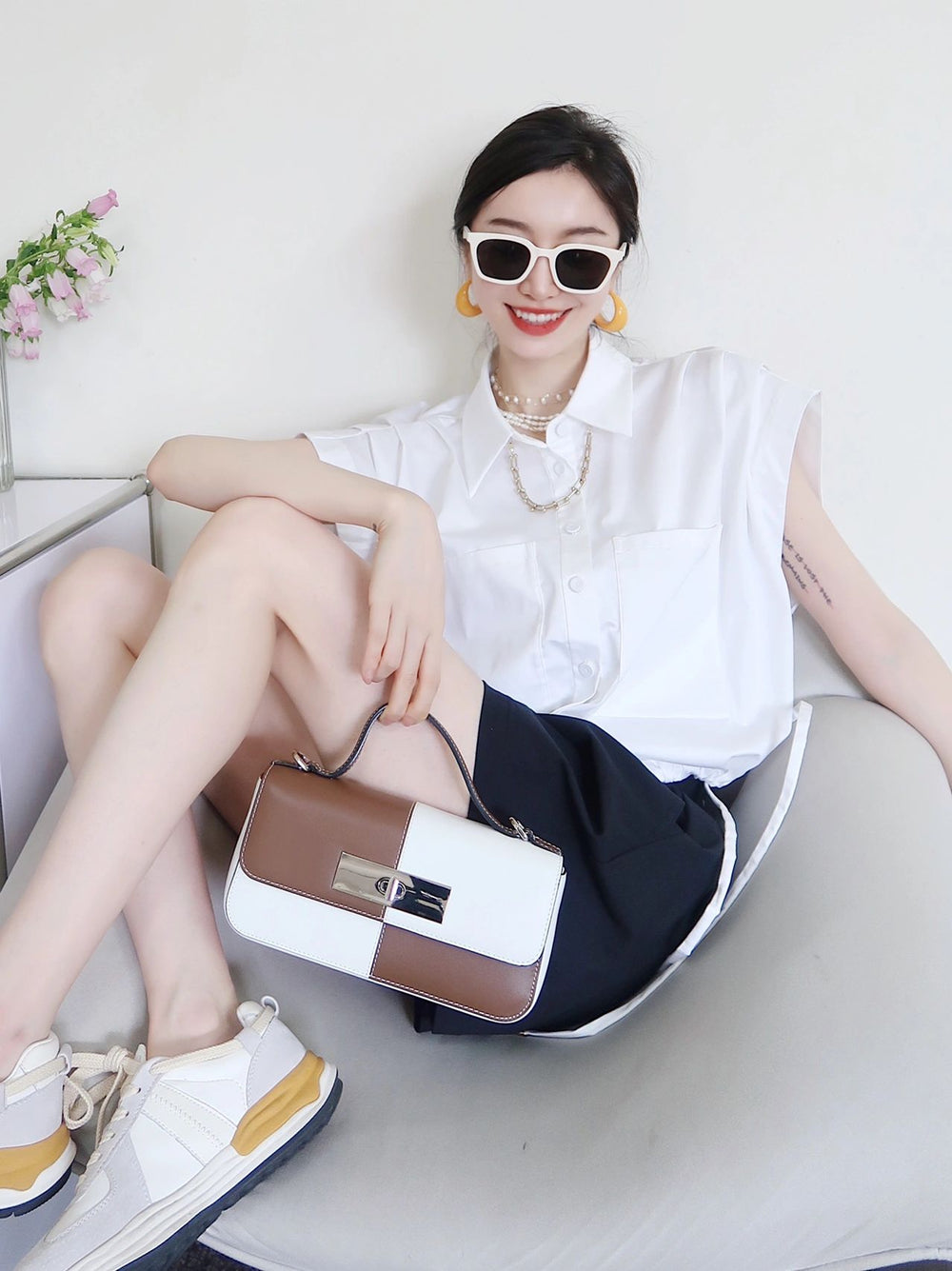 A fashionable lady sitting on a chair with her purse, exuding elegance and poise wearing her Korean fashion sunglasses.