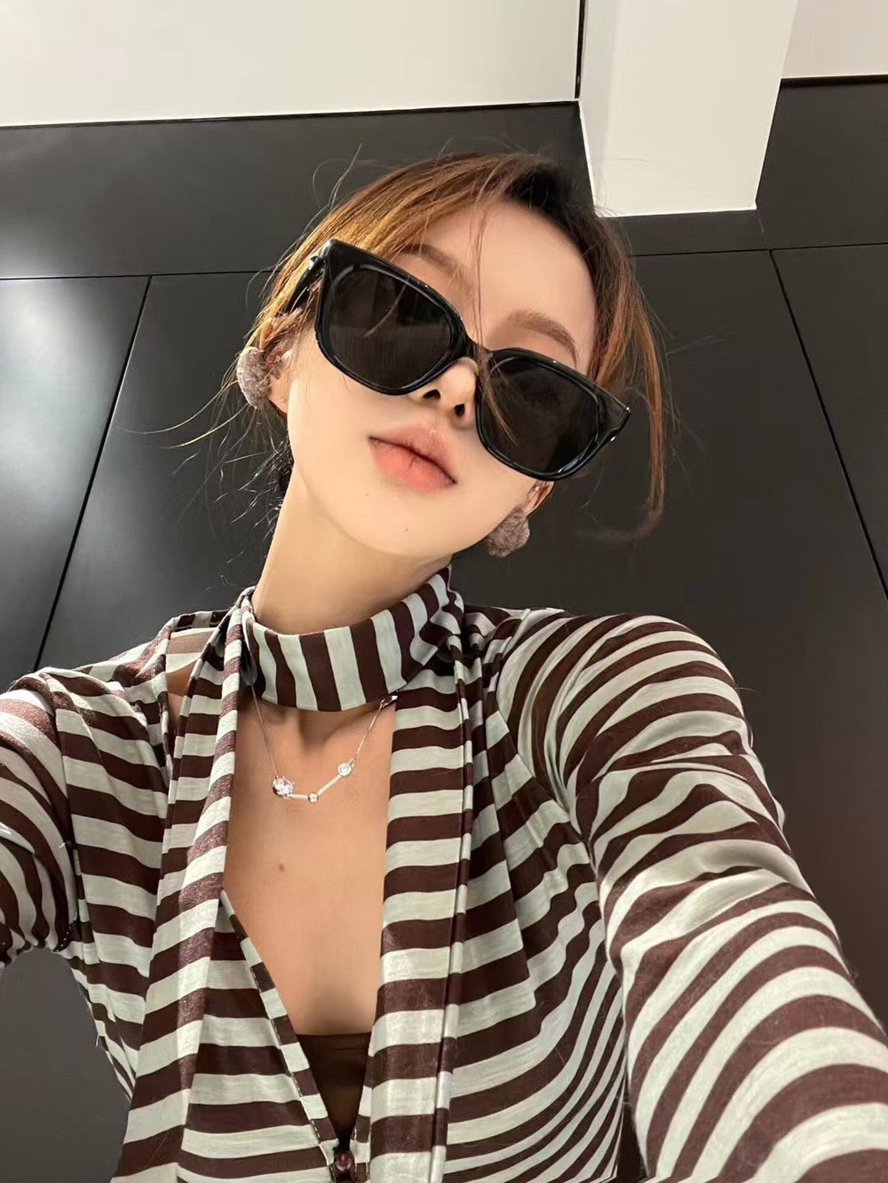 With an air of sophistication, a woman donning a striped shirt and trendy sunglasses exudes a timeless sense of style and grace.