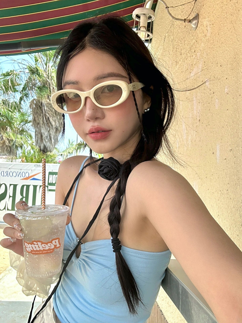 Witness the embodiment of luxury as a woman adorns herself with designer sunglasses and a fashionable tank top, exuding an air of opulence and refinement.