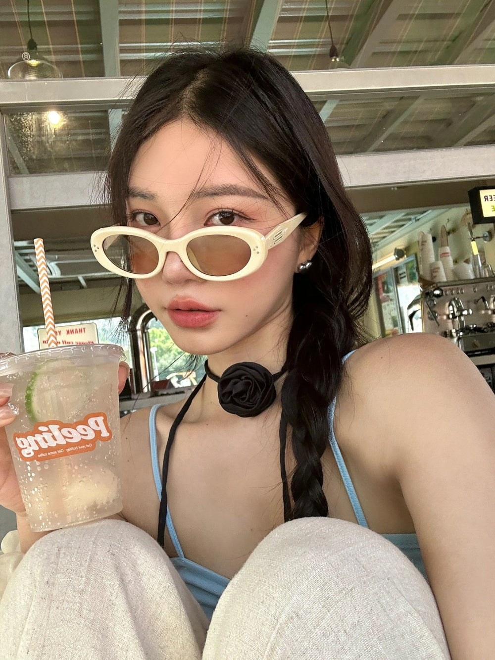 Stylish woman with Korean fashion sunglasses, enjoying a beverage in hand.