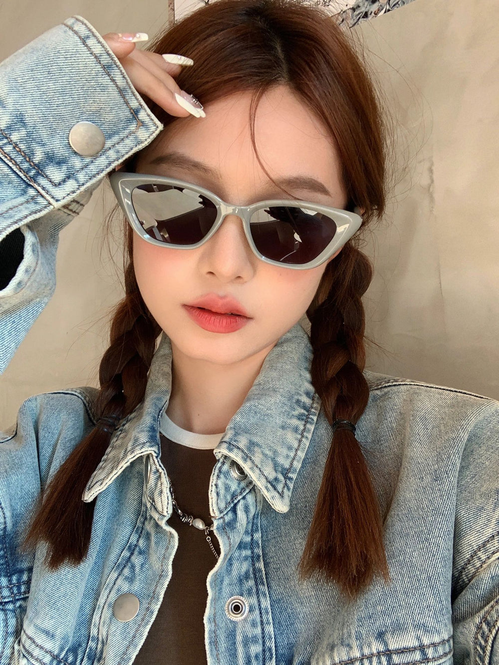 A stylish woman in trendy sunglasses and a denim jacket exudes coolness and fashion-forward vibes.