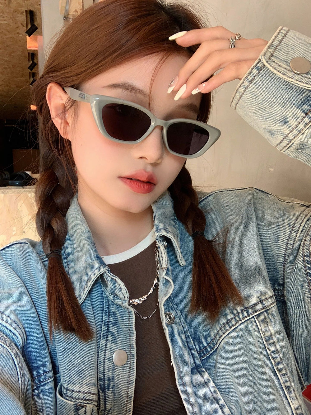 An image of a woman in a denim jacket and sunglasses, radiating a trendy and fashionable look.