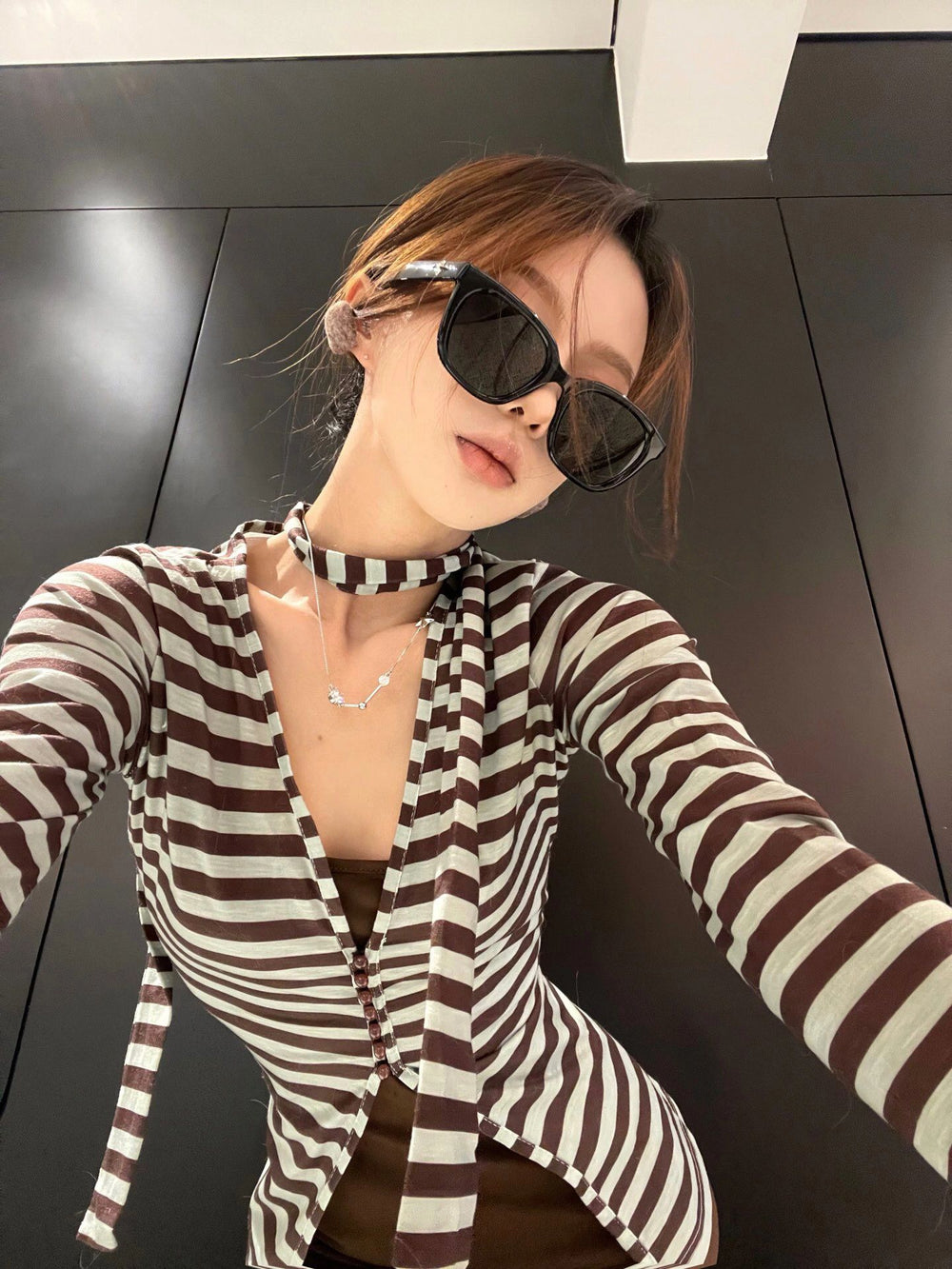 Effortlessly chic, a woman in a striped shirt and stylish sunglasses exudes an aura of luxury and elegance, captivating all who behold her.