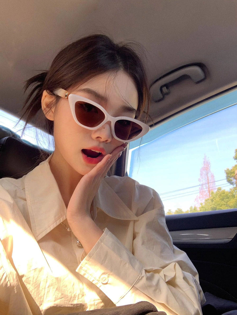 With an air of sophistication, a woman sporting trendy sunglasses reclines in the plush back seat of a luxurious automobile.