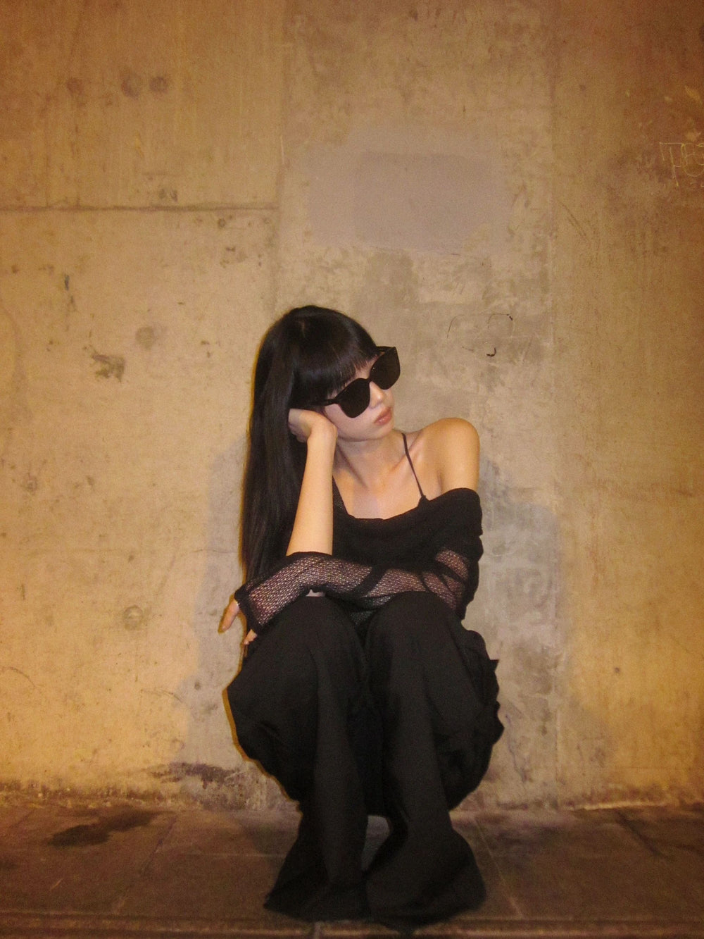 A woman in distress, sitting on the ground, holding her head in her hands wearing her Korean fashionable sunglasses.