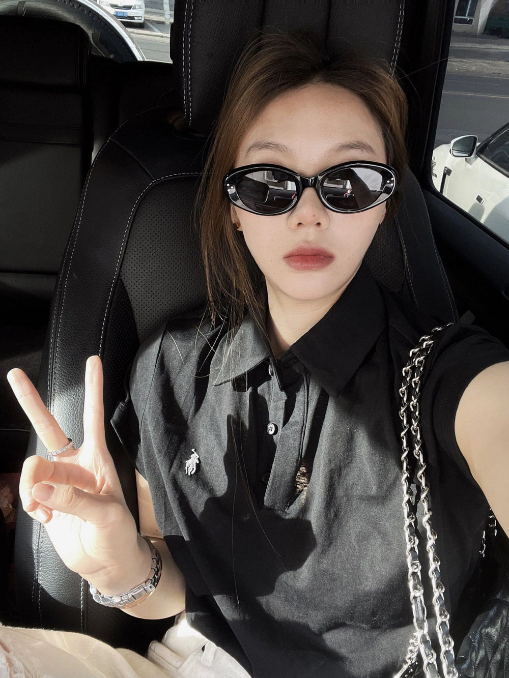 With an air of sophistication, a woman sporting trendy sunglasses and a sleek black shirt relaxes in the back seat of a luxurious car.