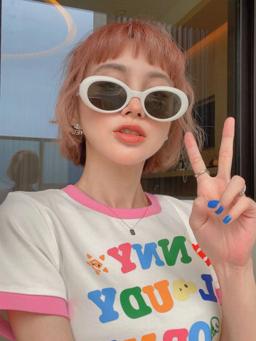 A woman wearing sunglasses and an NYC t-shirt, promoting poison sunglasses during mercury retrograde.