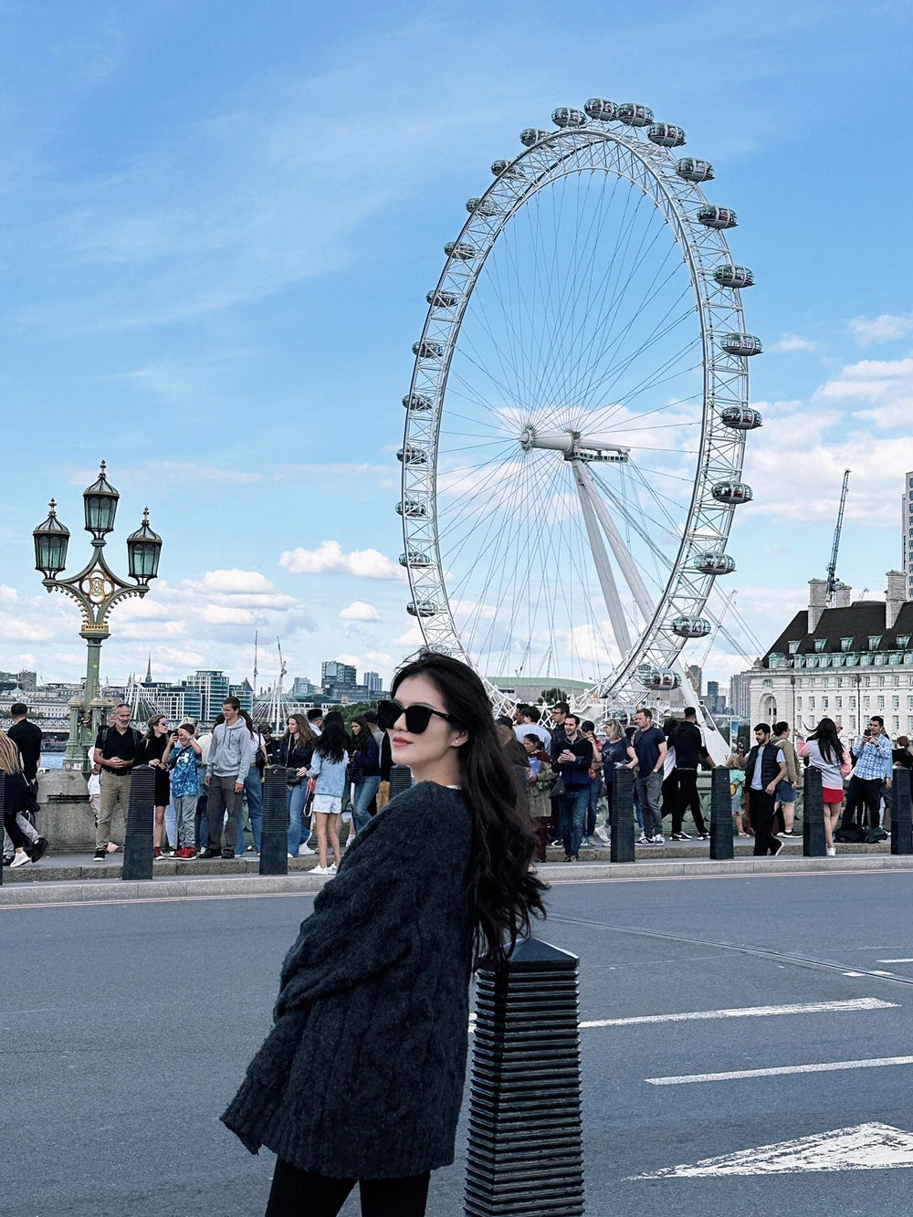 Fashionable woman with sunglasses standing in front of a ferris wheel.