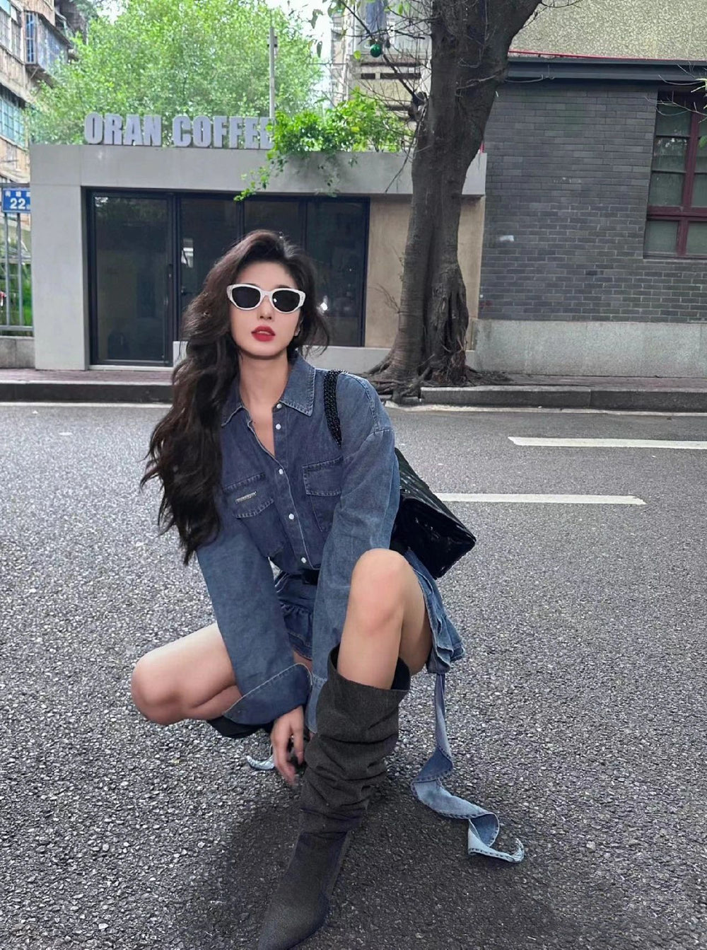 An alluring woman exuding sophistication, donning chic boots and a stunning sunglasses , seated gracefully on the vibrant street.