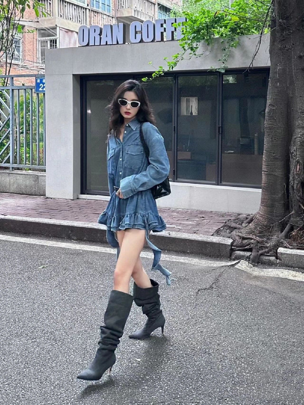 Mesmerizing onlookers, a woman in a stunning dress and fashionable sunglasses elegantly walks down the bustling street, exuding timeless charm.