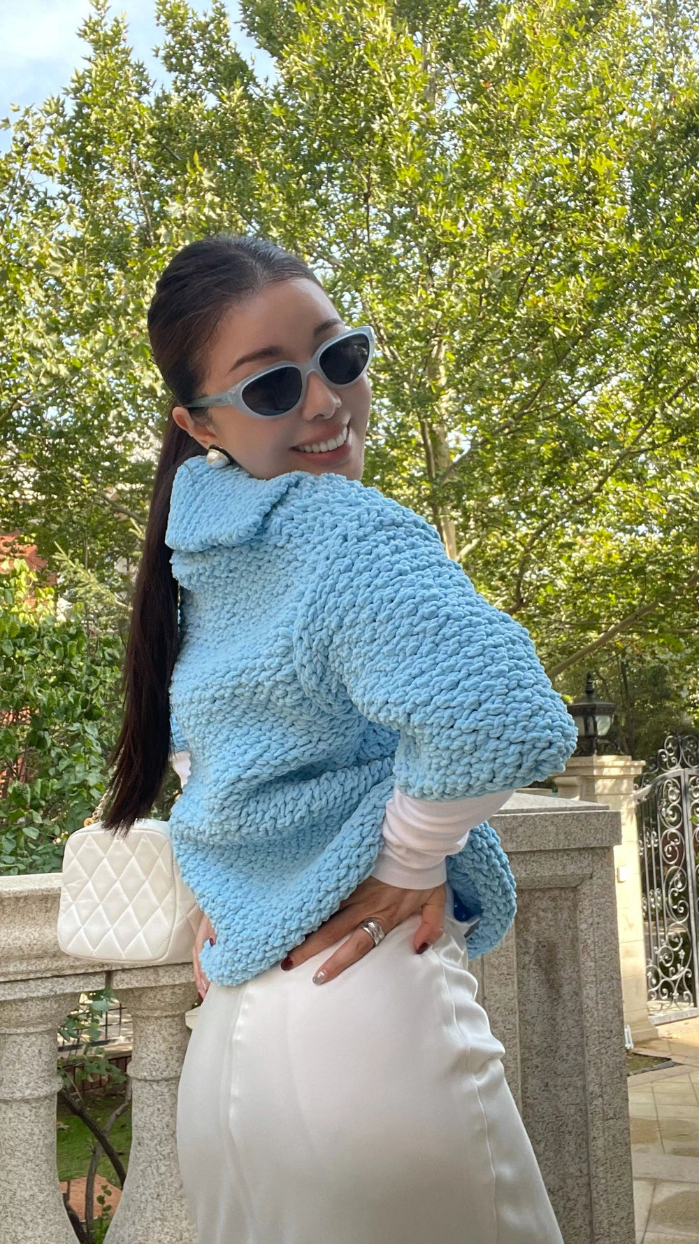 With her captivating blue sweater and fashionable sunglasses, this woman epitomizes timeless elegance and impeccable style.