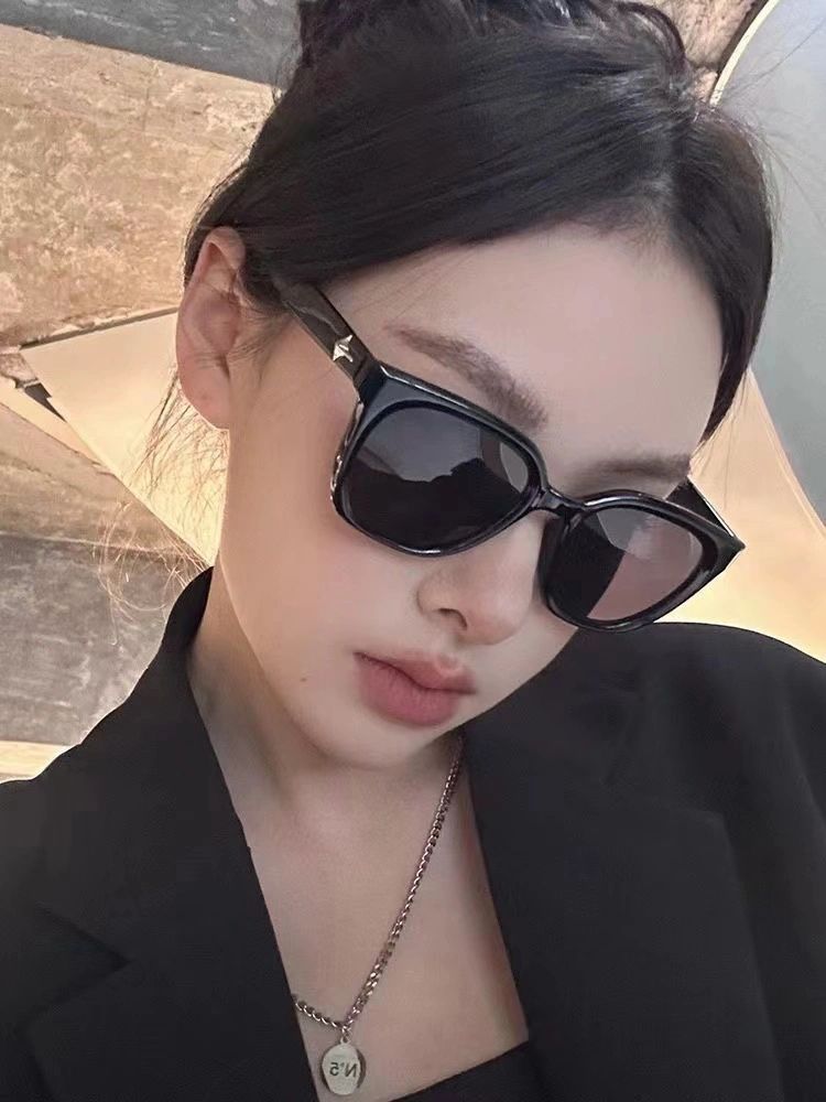 The epitome of sophistication, a woman dons a sleek black blazer and trendy sunglasses, exuding an aura of luxury and refinement.