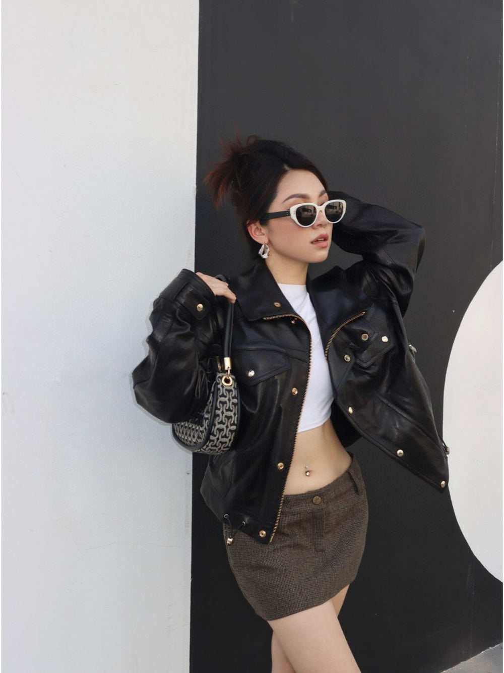 A vision of allure, a woman dons a chic black leather jacket and stylish sunglasses, epitomizing luxury and commanding attention with her impeccable fashion sense.