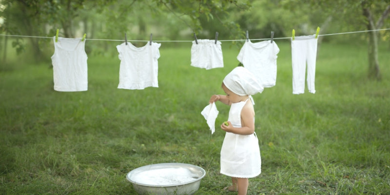 Little girl in white dress doing laundry outside line dry washing day
