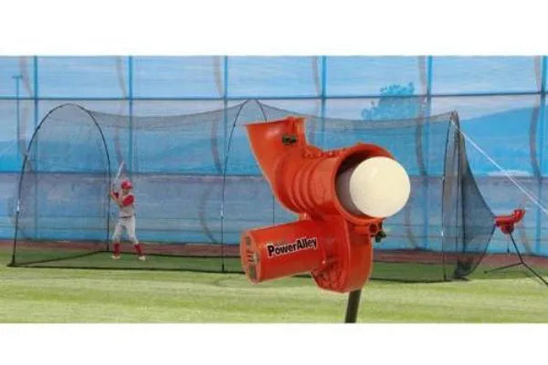 Power Alley Pitching Machine with adjustable pitch speed and PowerAlley Batting Package, designed for baseball training, featuring a batter in the background practicing in a netted cage.