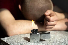 Gasoline lighter burns on table. Fire in background of sleeping guy. Party details. Smoking is harmful to health.