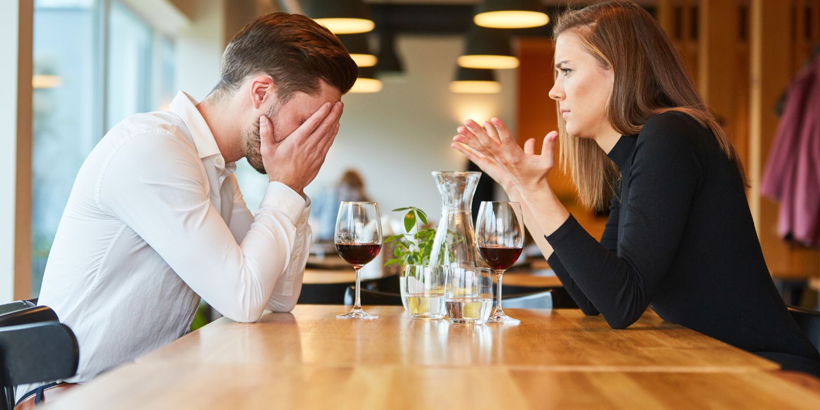 Un couple dans un restaurant, assis à une table, en train de se disputer.