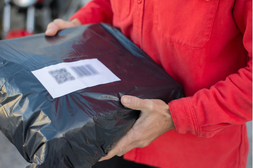 Discreet Unlabeled Black Package Being Delivered by Man in Red Shirt
