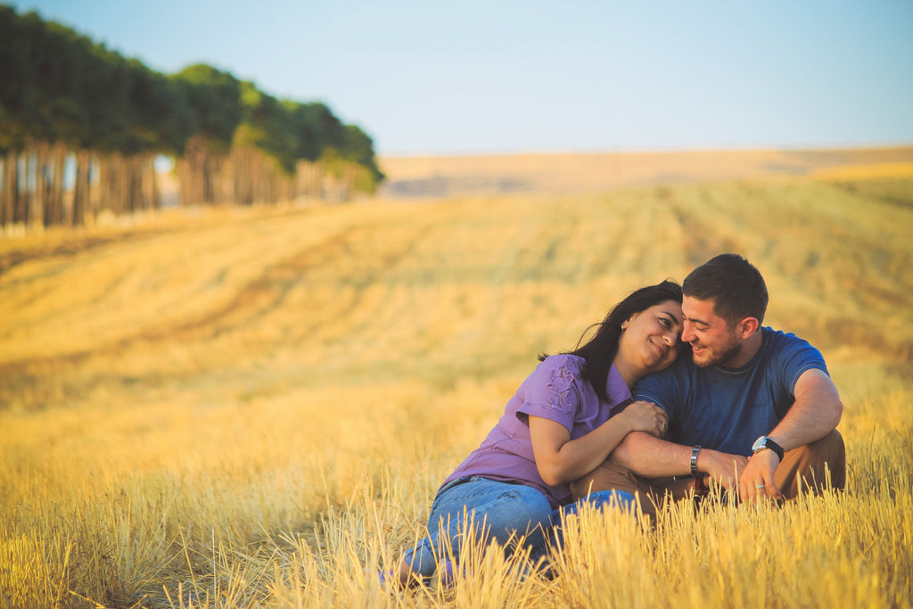 Woman Holding Man's Arm in Fields Sitting Down