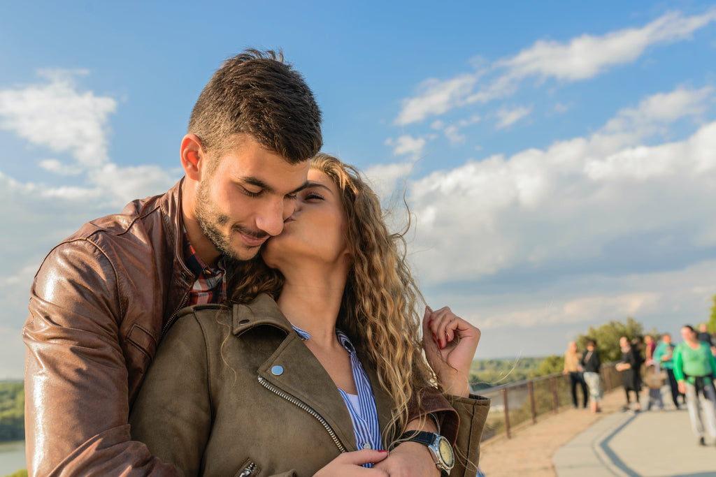 Woman Kissing Man Outdoors on Boardwalk