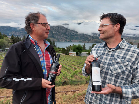Winemakers from ON and BC holding each others' bottles.