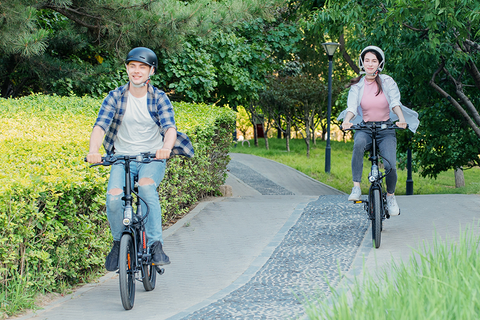 Paar rijdt samen op 5TH WHEEL Thunder 2 e-fietsen, genietend van een rit in het groene stedelijke landschap van de Benelux.