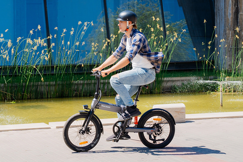 Persoon rijdt op een 5TH WHEEL Thunder 2 elektrische fiets langs een stedelijke waterpartij, duurzaam reizen in Nederland.