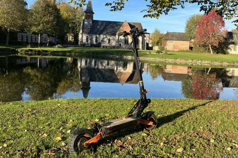 Elektrische step aan de oever van een meer die rust en de naadloze integratie van e-mobiliteit in de pittoreske omgeving van de Benelux weerspiegelt.