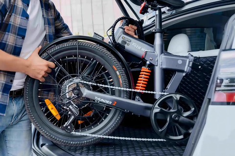 Man plaatst een opvouwbare 5TH WHEEL Thunder 2 e-fiets in de kofferbak van een auto, perfect voor mobiliteit in de Benelux.