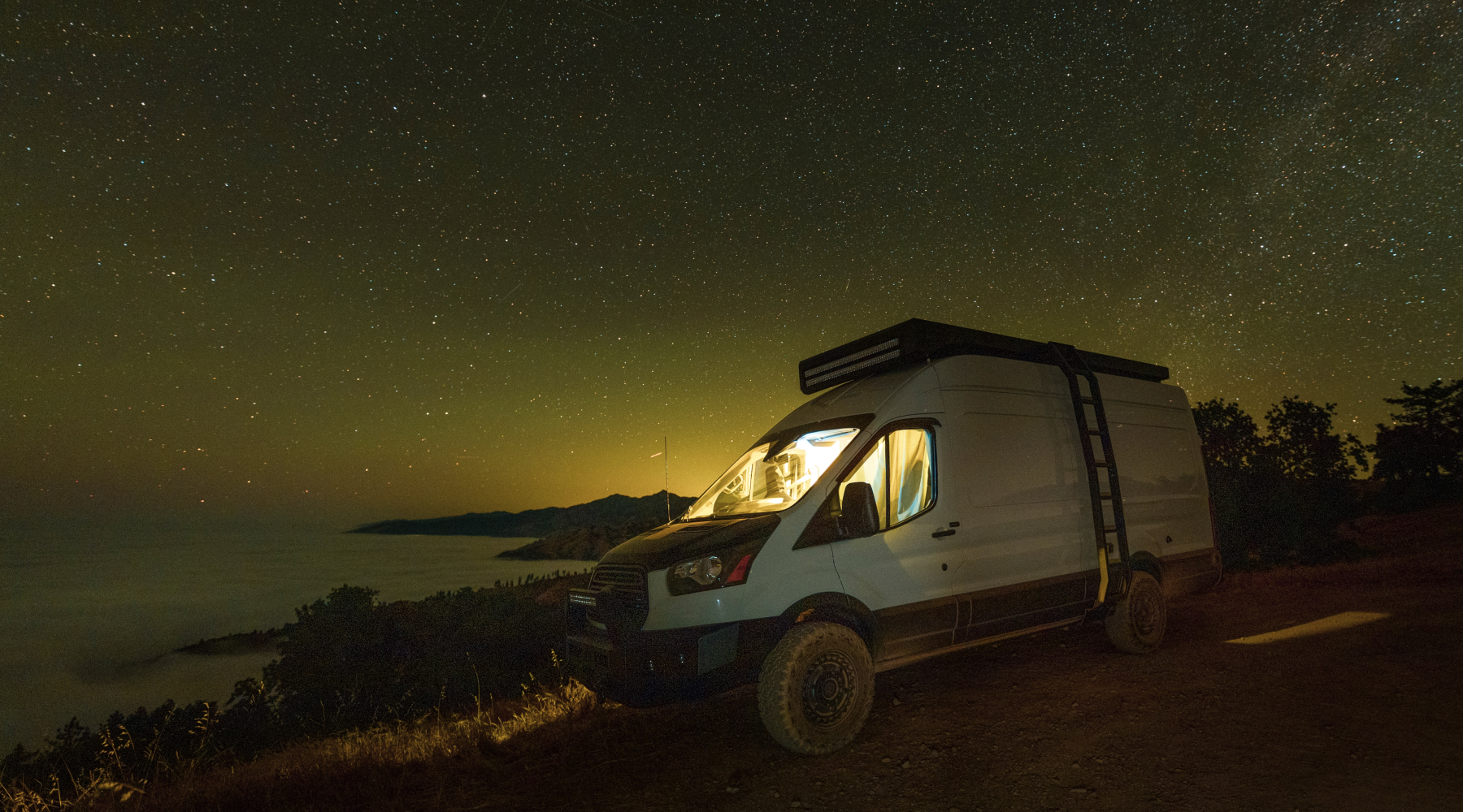 White sprinter van camping at night on California Coast