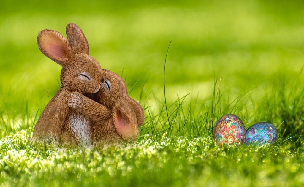 a statuette of two bunnies hugging in grass