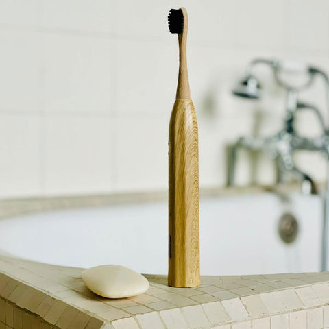 A bamboo electric toothbrush in a minimalist bathroom