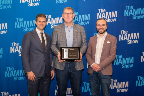 •	Rob Hanson, centre, and Mark Good, right, of John Packer Musical Instruments, receive the company's NAMM Show Milestone Award, marking 50 years in business, from NAMM CEO, John Mlynczak.