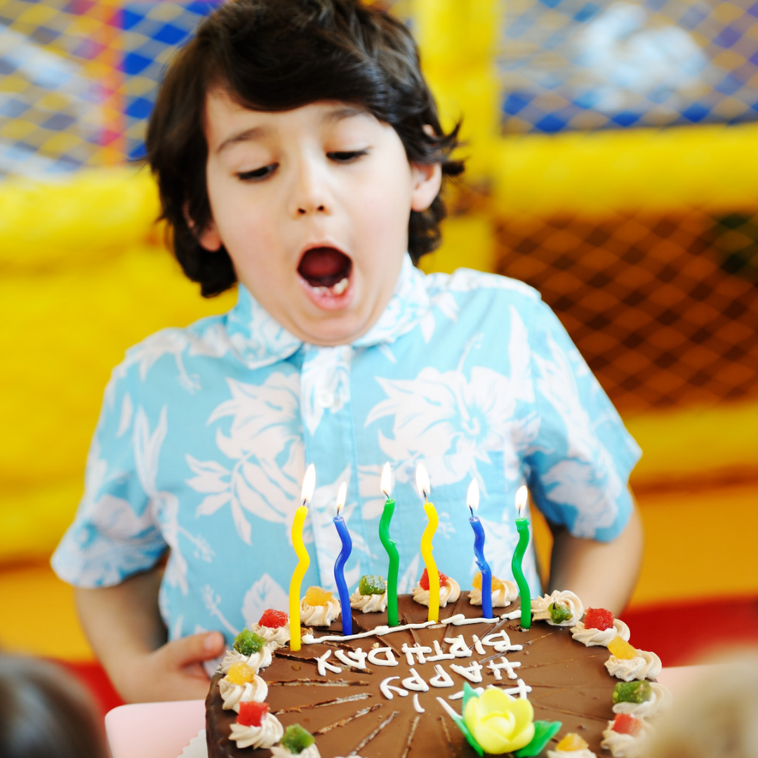 A young boy blowing out candles on a birthday cake.